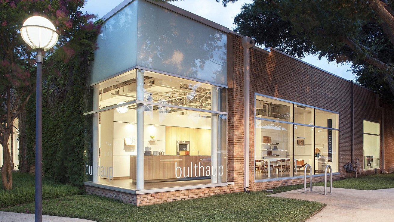 View of exterior of bulthaup Dallas showroom at dusk with b3 display kitchen glowing warm and welcoming.